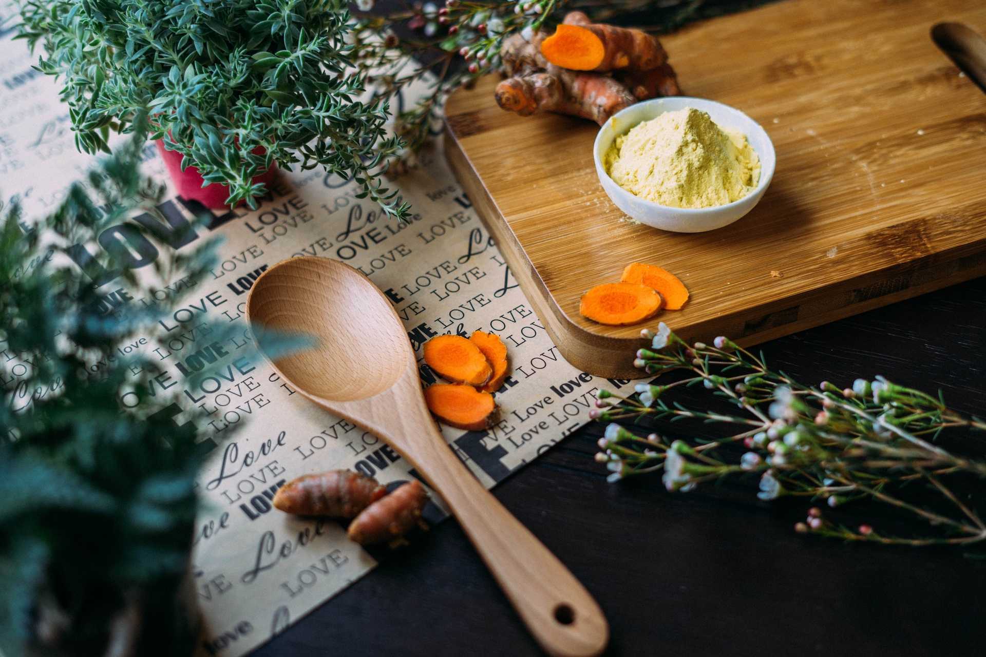 Herbs, turmeric, chopping board, wooden spoon on a table