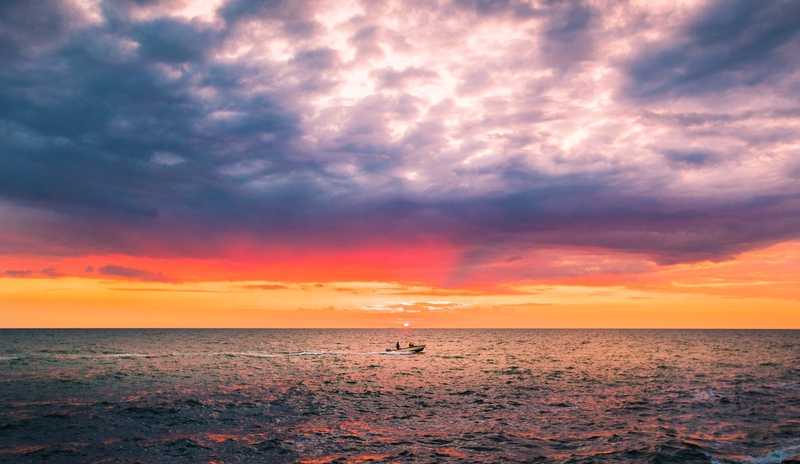 Boat on ocean overlooking sunset